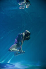 Fototapeta na wymiar a girl under water, in an aquarium, in a pool in flesh-colored underwear naked swims like a mermaid