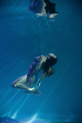 Obraz na płótnie Canvas a girl under water, in an aquarium, in a pool in flesh-colored underwear naked swims like a mermaid