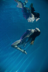 a girl under water, in an aquarium, in a pool in flesh-colored underwear naked swims like a mermaid