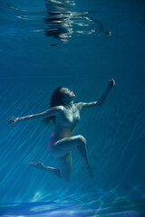 Fototapeta na wymiar a girl under water, in an aquarium, in a pool in flesh-colored underwear naked swims like a mermaid
