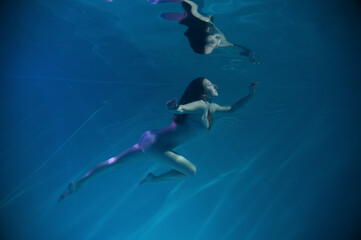 Obraz premium a girl under water, in an aquarium, in a pool in flesh-colored underwear naked swims like a mermaid