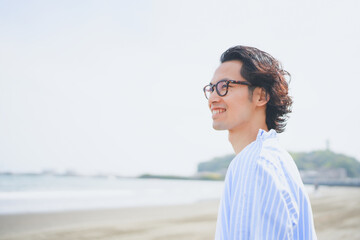 夏の海岸を歩く青いストライプシャツを着た男性