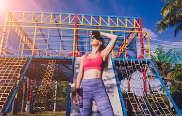 Athletic young woman working out and climbing at the artificial rock in training camp.