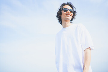 夏の海岸を歩くサングラスをかけた男性