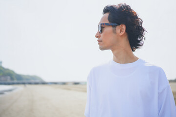 夏の海岸を歩くサングラスをかけた男性