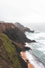 High limestone cliffs sinking into the Atlantic Ocean in the Algarve region, southwestern Portugal. Rainy weather. Wandering along the Fisherman Trail