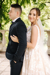 Naklejka premium Portrait of newlyweds stand on balcony and dreaming. Handsome groom and beautiful bride on their wedding day