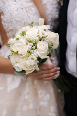 Close-up of bride hold wedding bouquet in hands. Beautiful white flowers 