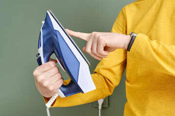 Unrecognisable man touching the sole of an iron with finger