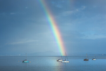 Beautiful rainbow in the sky arching over fishing boats and the Firth of Forth in the quaint village of Aberdour, Fife, Scotland, UK.