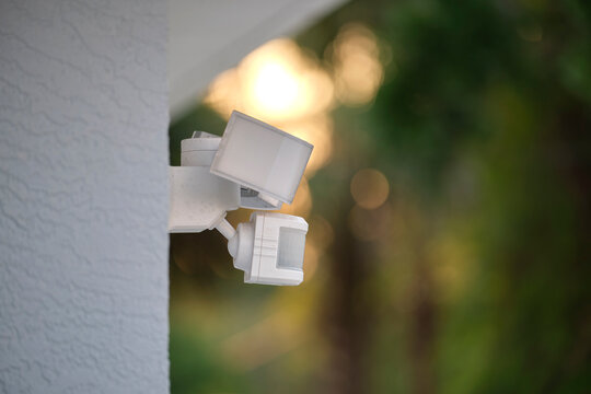 Motion sensor with light detector mounted on exterior wall of private house as part of security system