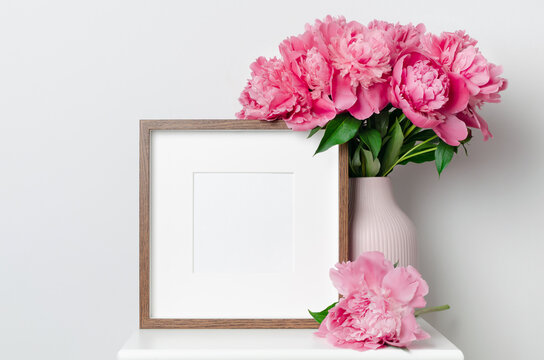 Wooden square artwork frame mockup with peony flowers in white interior, blank passepartout frame mockup with copy space