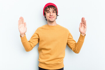 Young caucasian man isolated on blue background holding something little with forefingers, smiling and confident.