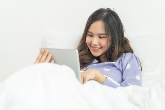 Asian woman watching movie in tablet on the bed at home