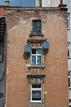 Old tenement house in poor condition with satellite dishes on the wall