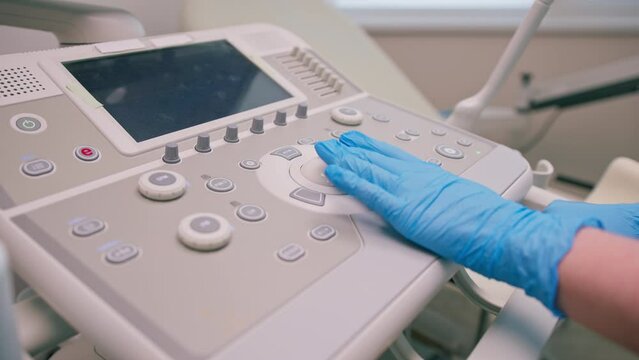 A gynecologist uses a transvaginal ultrasound device presses buttons takes a picture of the patient's internal organs in the clinic close-up