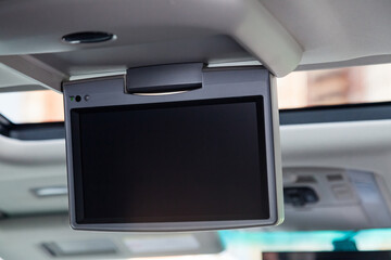 Entertainment system for rear passengers in a car with monitor mounted on the ceiling for watching...