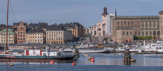 Boats moored at the jetties at the bridge Skeppsholmsbron, the old town Gamla Stan in the...