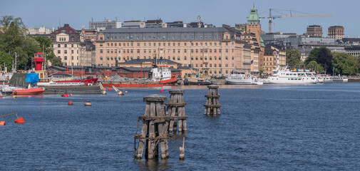 Three old wood dolphins and old sailing boats moored at a pier on the maritime island Skeppsholmen, a sunny summer day in Stockholm © Hans Baath