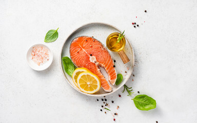 Fresh raw salmon steaks with spices, lemons and pink salt on white plate. Top view of fish on white background. Keto recipe. - 609623186