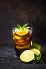 Cuba Libre alcoholic cocktail, iced drink on dark background. Vertical image.