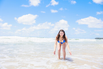 Fototapeta na wymiar 海辺でカメラに向かって水をかける水着のセクシーな女の子