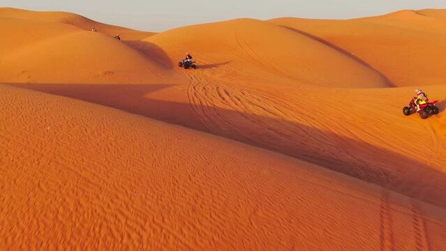 A drone flies over quad bikes driving through the sand dunes of the desert in the United Arab Emirates