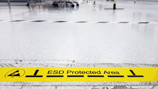 On a floor of the electronics manufacturing covered industrial linoleum pastes a yellow tape with a standard warning text: "ESD Protected Area",Blurred background,copy space for texture