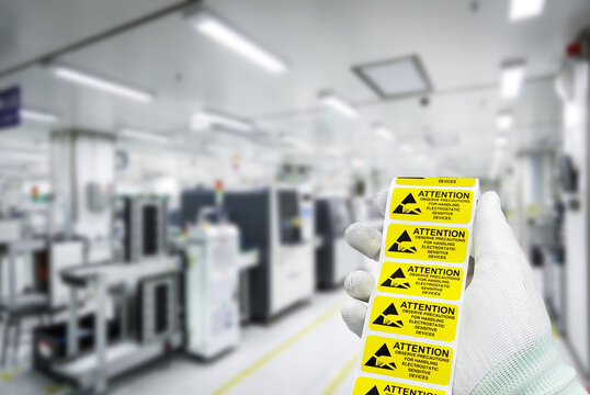 Hand holding "CAUTION Electrostatic Sensitive Devices" label at static free workstation,Antistatic area in electronic industry.