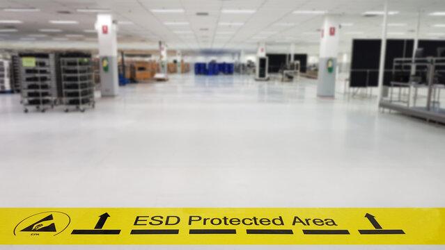 On a floor of the electronics manufacturing covered industrial linoleum pastes a yellow tape with a standard warning text: "ESD Protected Area",Blurred background,copy space for texture