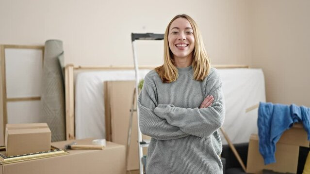 Young blonde woman smiling confident standing with arms crossed gesture at new home