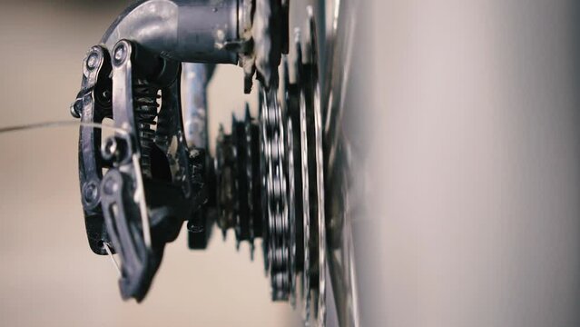 Close-up of bicycle chain passing through the roller of the rear derailleur and down the cassette from the large sprocket to small sprocket. Bicycle gear and cassette. Bicycle repair. Slow motion