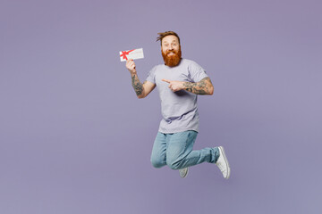 Full body young redhead bearded man wear violet t-shirt casual clothes jump high hold gift...
