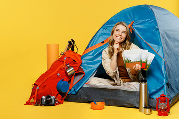 Full body fun young woman sit near bag with stuff tent hold freeze-dried food isolated on plain yellow background Tourist lead active lifestyle walk on spare time Hiking trek rest travel trip concept.