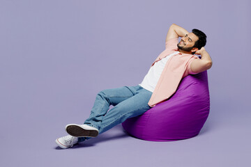Full body young Indian man he wear pink shirt white t-shirt casual clothes sit in bag chair hold...