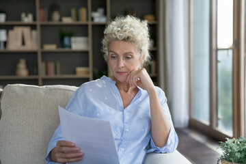 Serious pretty blonde senior woman reading paper document, getting letter, medical insurance...