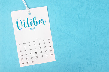 The 2023 October calendar page hanged on white rope  on blue background.
