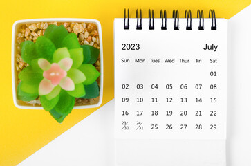 The July 2023 Monthly desk calendar for 2023 year with small tree on yellow background.