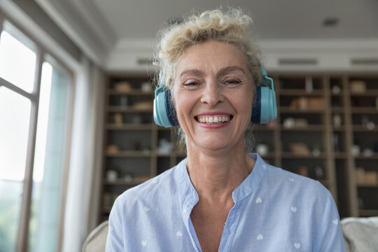 Cheerful Beautiful Mature Blonde Woman Using Wireless Headphones For Internet Connection, Looking At Camera With Toothy Smile, Laughing. Video Call Screen Head Shot Portrait