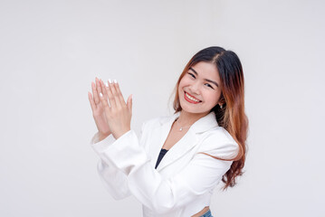 A young woman with head tilted clapping while looking at the camera. Isolated on a white background.