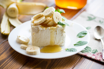 Portion of homemade milk curd with banana slices and honey
