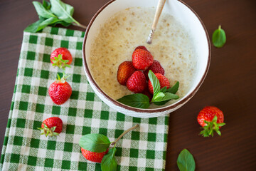 cooked diet oatmeal in a bowl with fresh ripe strawberries