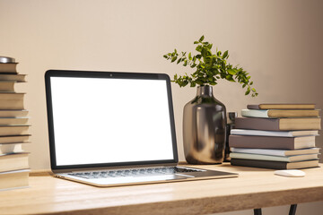 Side view of student wooden desk with white screen laptop and a lot of books on beige wall background in modern cozy interior with lamp and plant, mockup. Education and learning concept. 3D Rendering