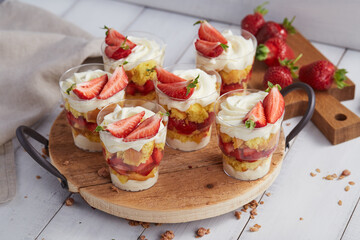 Glasses with strawberry trifle desserts on wooden table