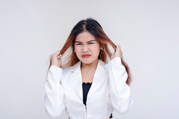 A frustrated and irritated young woman pulling her hair with both hands in annoyance. Isolated on a white background.
