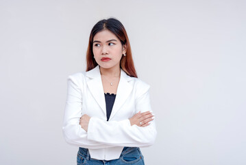An irked and irritable young woman glancing at her left with arms crossed. Isolated on a white background. - obrazy, fototapety, plakaty