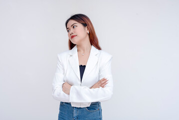 A displeased young woman looking to her right side with arms crossed in annoyance. Isolated on a white background. - obrazy, fototapety, plakaty