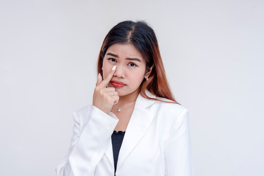 A sarcastic young woman pulling her lower eyelid with a finger to mock someone. Isolated on a white background.