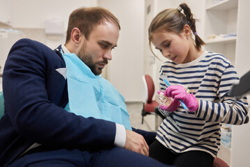 A small curly girl and her father play a dentist. happy relationship.