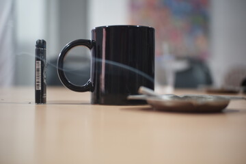 Enjoying a cup of coffee with a cigarette on the table.